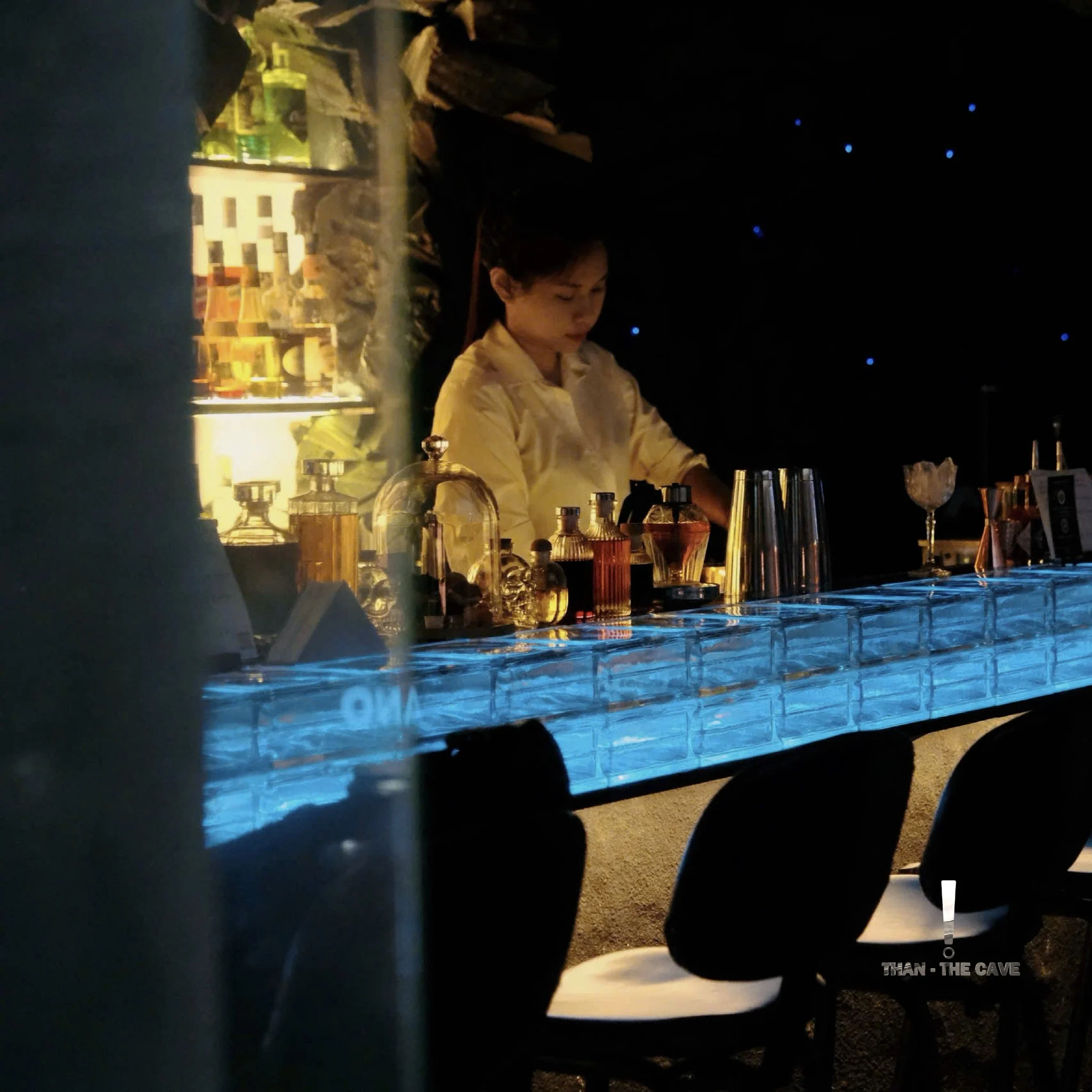Bartender working behind the blue glass bar